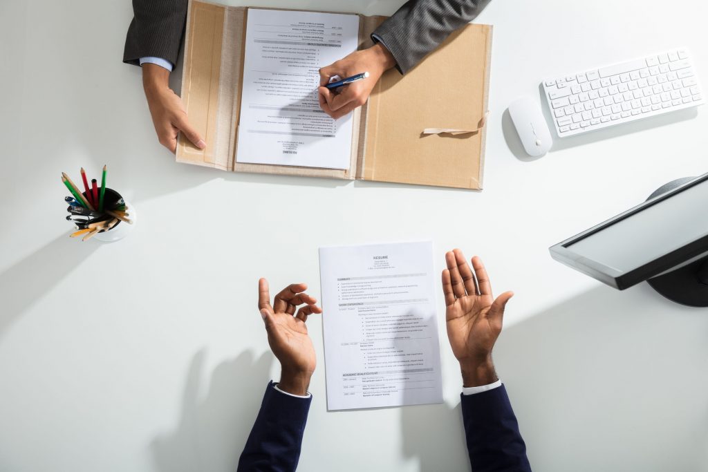 Businessperson And Candidates Hand Over White Desk