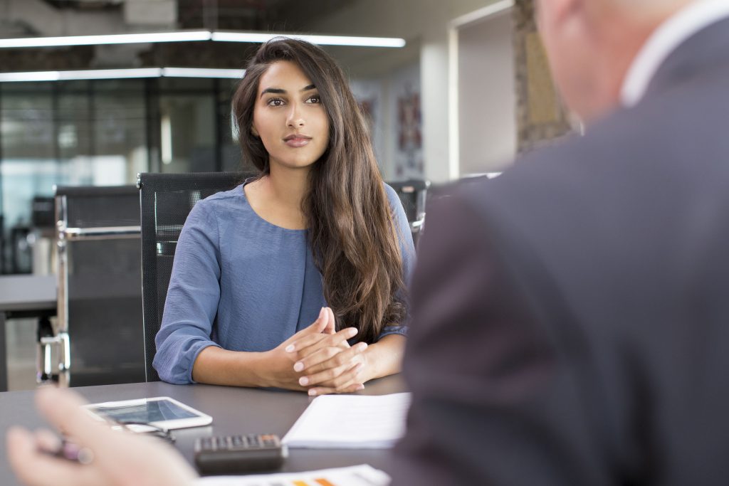 100630264 - focused indian female customer meeting with financial advisor. young beautiful candidate at job interview in modern office space. business consulting or employment concept