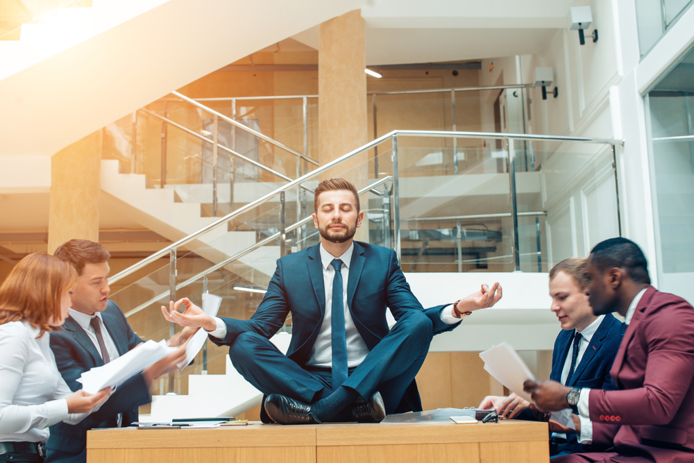 Colleagues meeting around table with leader meditating