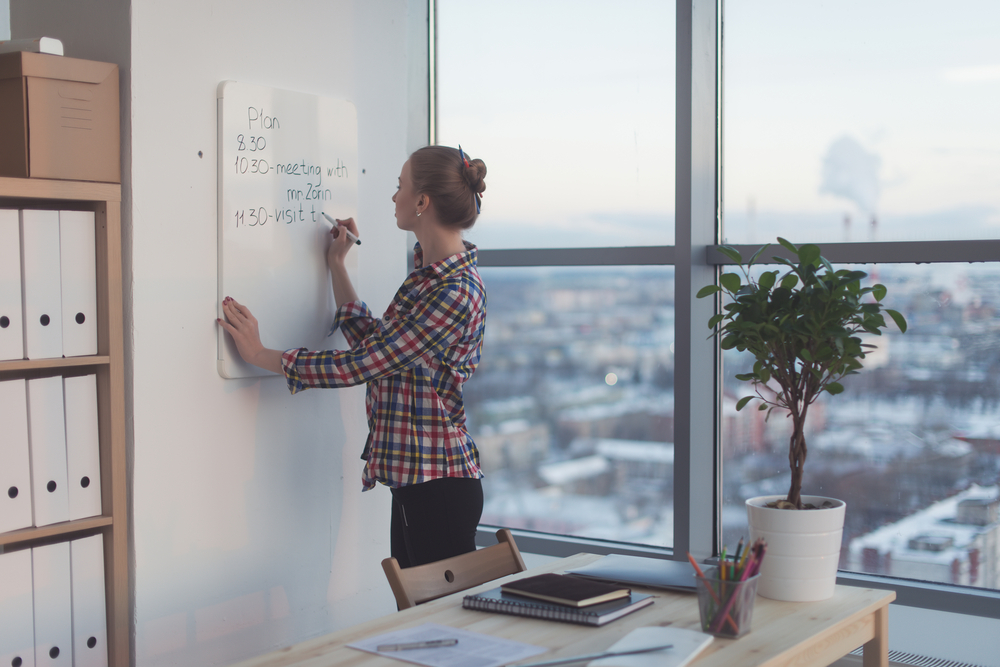 Woman in office planning schedule on whiteboard