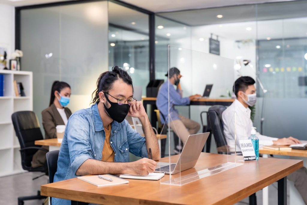 Group of interracial business worker team wear protective face mask in new normal office with social distance practice with hand sanitiser alcohol gel on table prevent coronavirus COVID-19 spreading